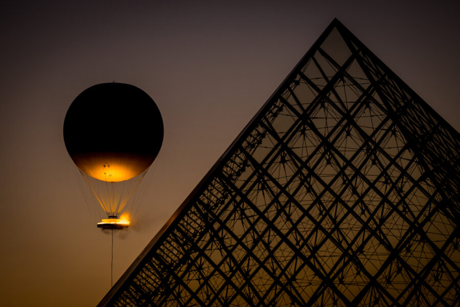 Letní olympijské hry v Paříži, 5. srpna 2024, Paříž, Francie. Vznášející se olympijský oheň vedle pyramidy u muzea Louvre v centru Paříže.